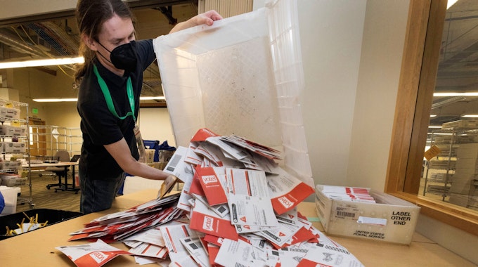 Das undatierte Symbolfoto zeigt einen Wahlhelfer mit einer Kiste voller Stimmzettel.