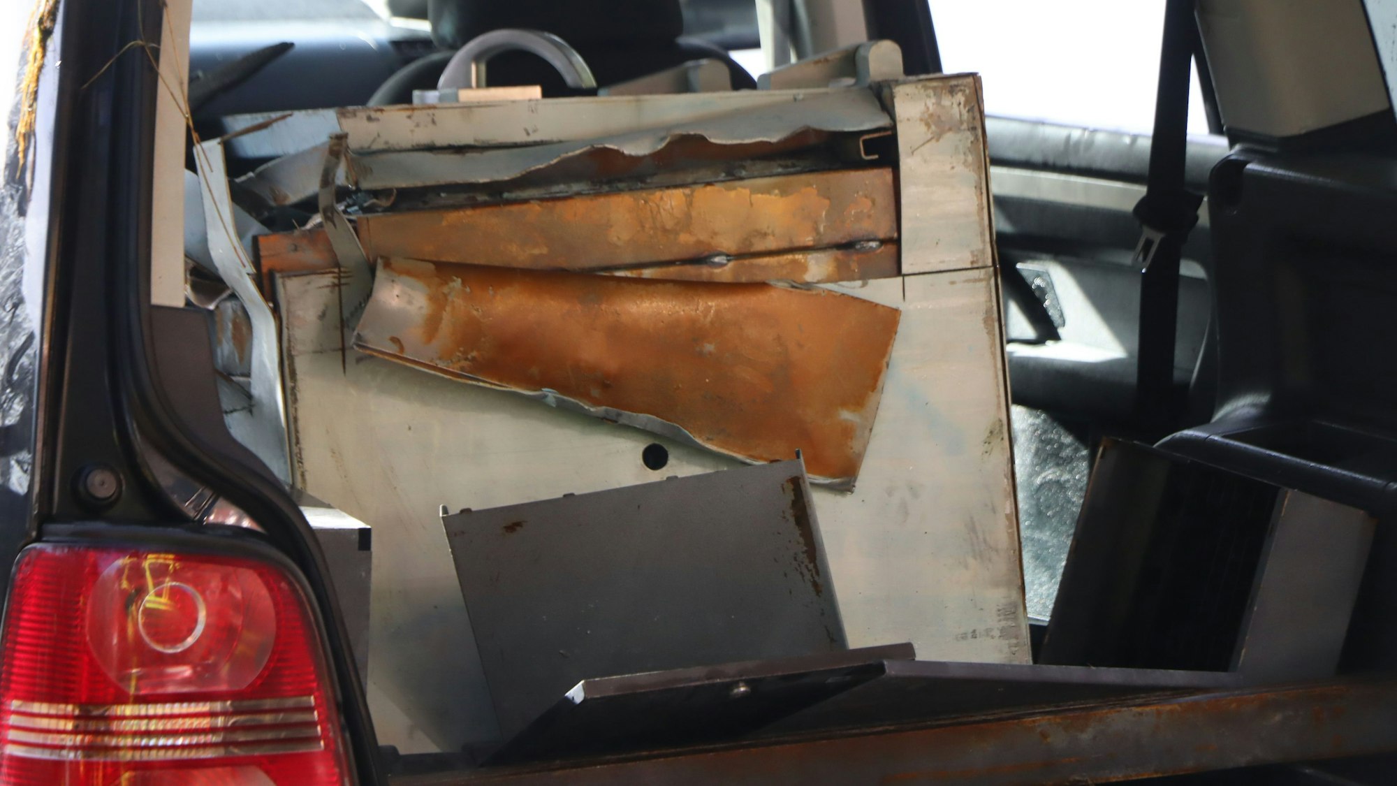 Im Kofferraum und auf der Rückbank eines Autos liegt ein stark beschädigter, weißer Tresor.