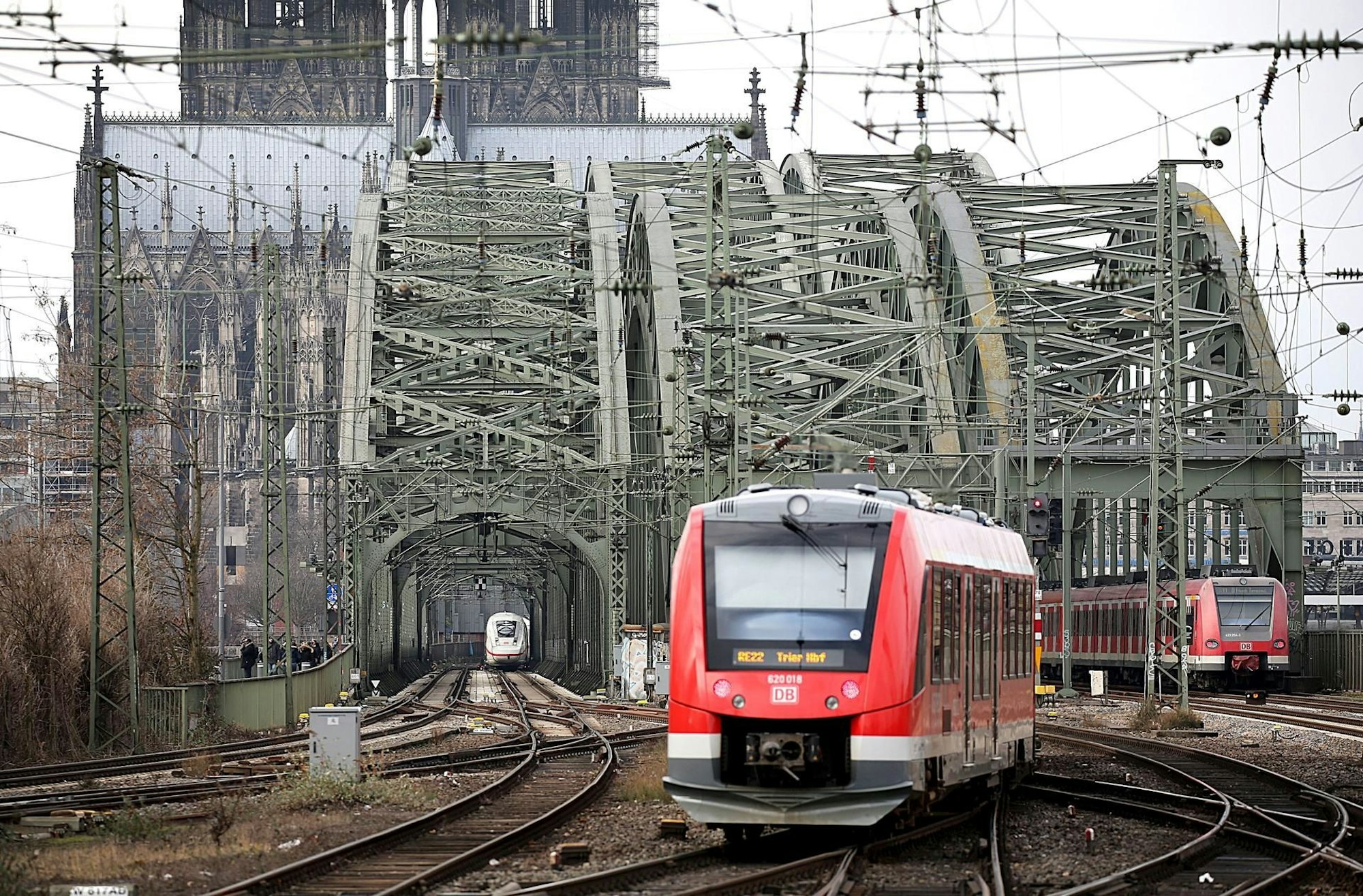 Züge fahren über die Schienen der Hohenzollernbrücke in Köln, im Hintergrund ist der Kölner Dom zu sehen.