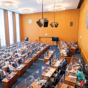 Der Ratssaal im spanischen Bau. Zahlreiche Stadträte sitzen an ihren Plätzen und verfolgen die Kölner Ratssitzung hinter Glasscheiben.