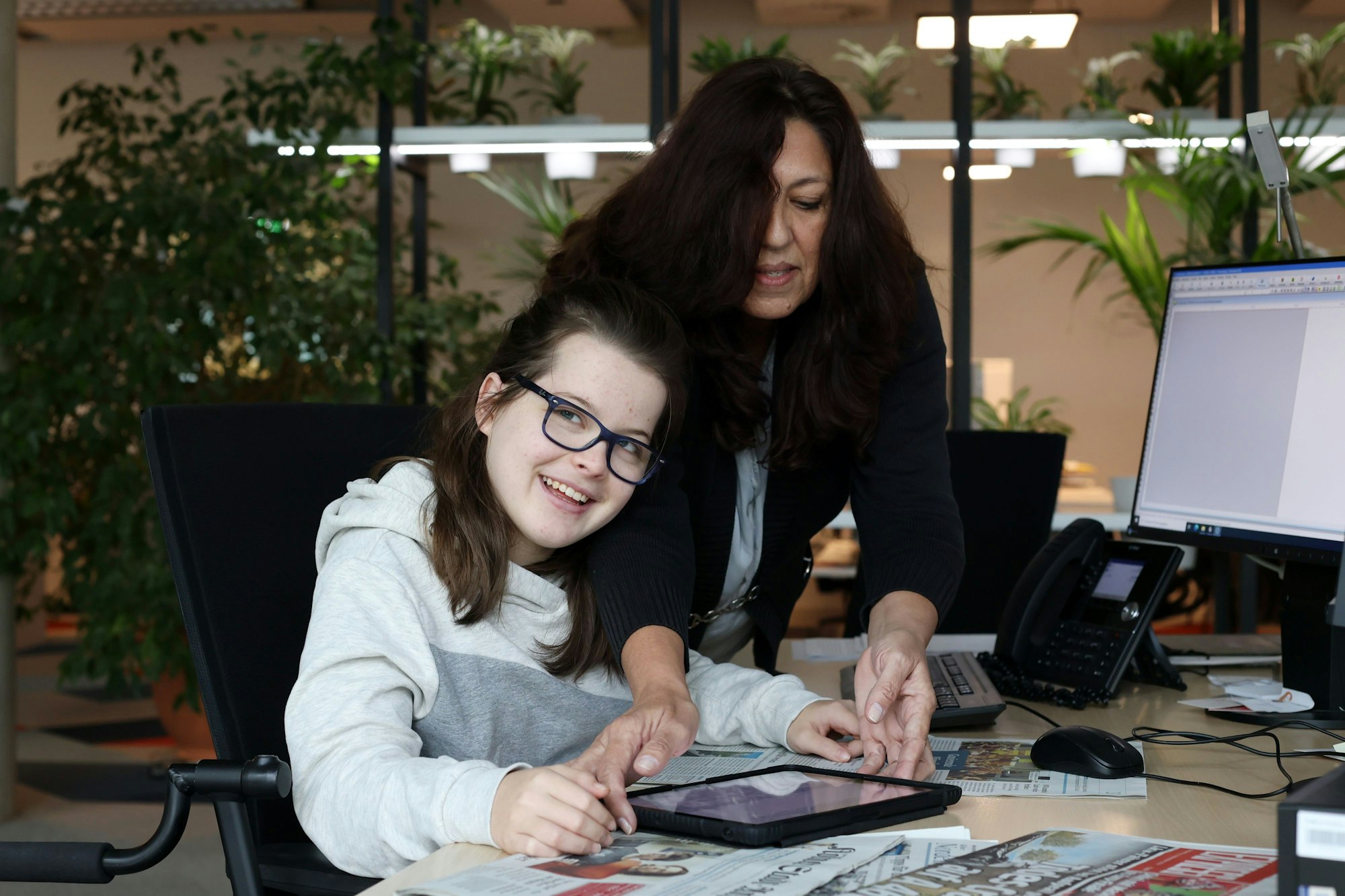 Aimées Schulbegleiterin Josi hilft Aimée am Schreibtisch, das iPad zu bedienen und die Zeitungen zu lesen.