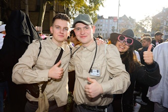 Zwei junge Männer tragen Ranger-Kostüme mit beigen Oberhemden.