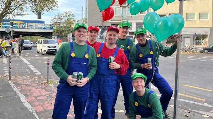 Sechs Freunde in Kostümen von Mario und Luigi posieren in Köln für die Kamera.