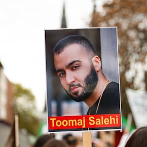 Ein Demonstrierender hält ein Schild mit dem Portrait des iranischen Rapper Toomaj Salehi bei einer Demonstration in Köln in die Höhe.&nbsp;