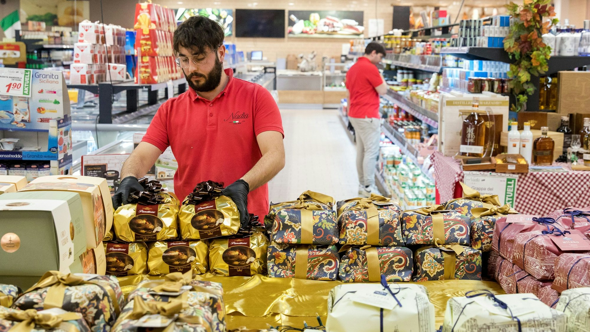 Mitarbeiter Salwatore Siciliano stapelt im italienischen Supermarkt Nadia Feinkost in Köln-Mülheim den Weihnachtskuchen Panettone.