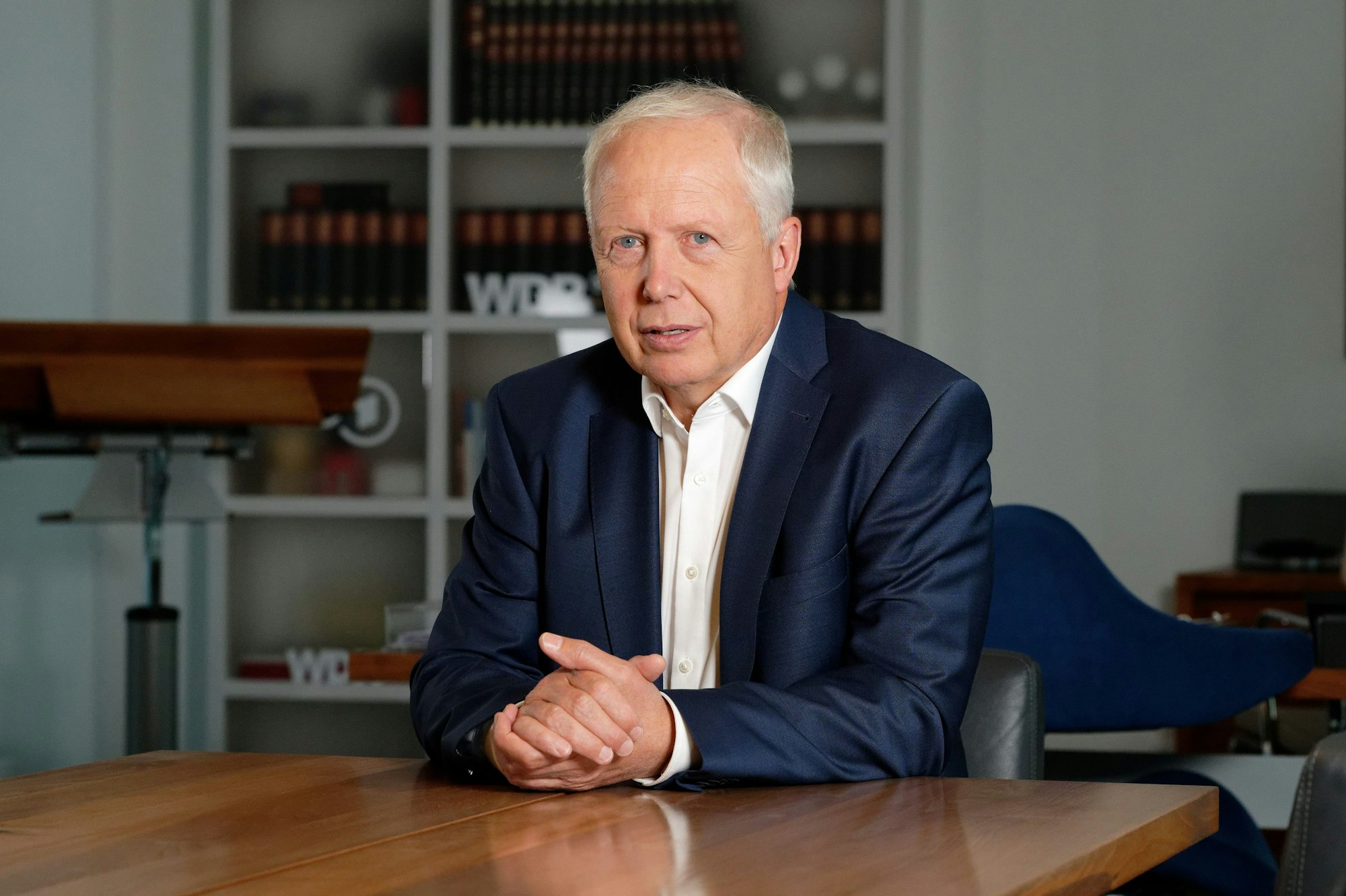 Tom Buhrow, Intendant des Westdeutschen Rundfunks (WDR), sitzt in seinem Büro im Gebäude des WDR. Er trägt einen blauen Anzug.
