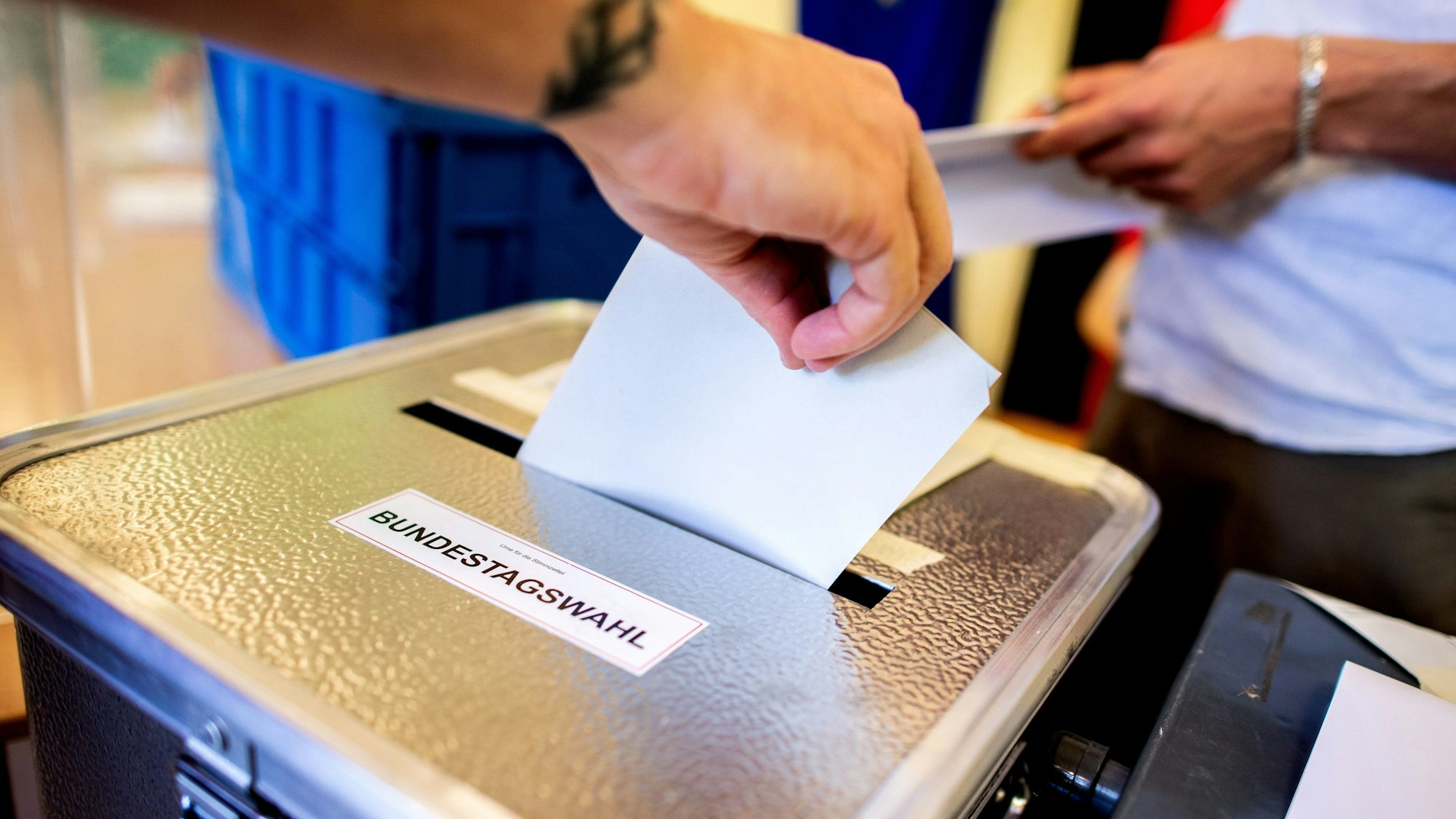 Ein Wähler wirft in einem Wahllokal, das im Klassenraum einer Grundschule im Stadtteil Prenzlauer Berg untergebracht ist, seinen Stimmzettel für die Bundestagswahl in eine Wahlurne. (Symbolbild)
