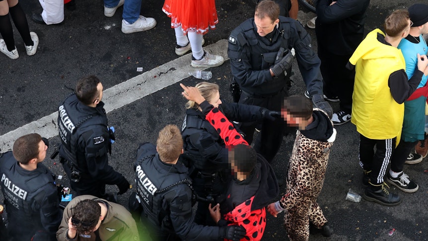 Polizisten diskutieren mit verkleideten Feiernden.
