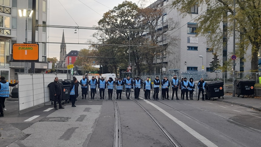 Mehrere Mitarbeiter des Ordnungsamts stehen mit blauen Warnwesten an den Zugängen zur Zülpicher Straße.