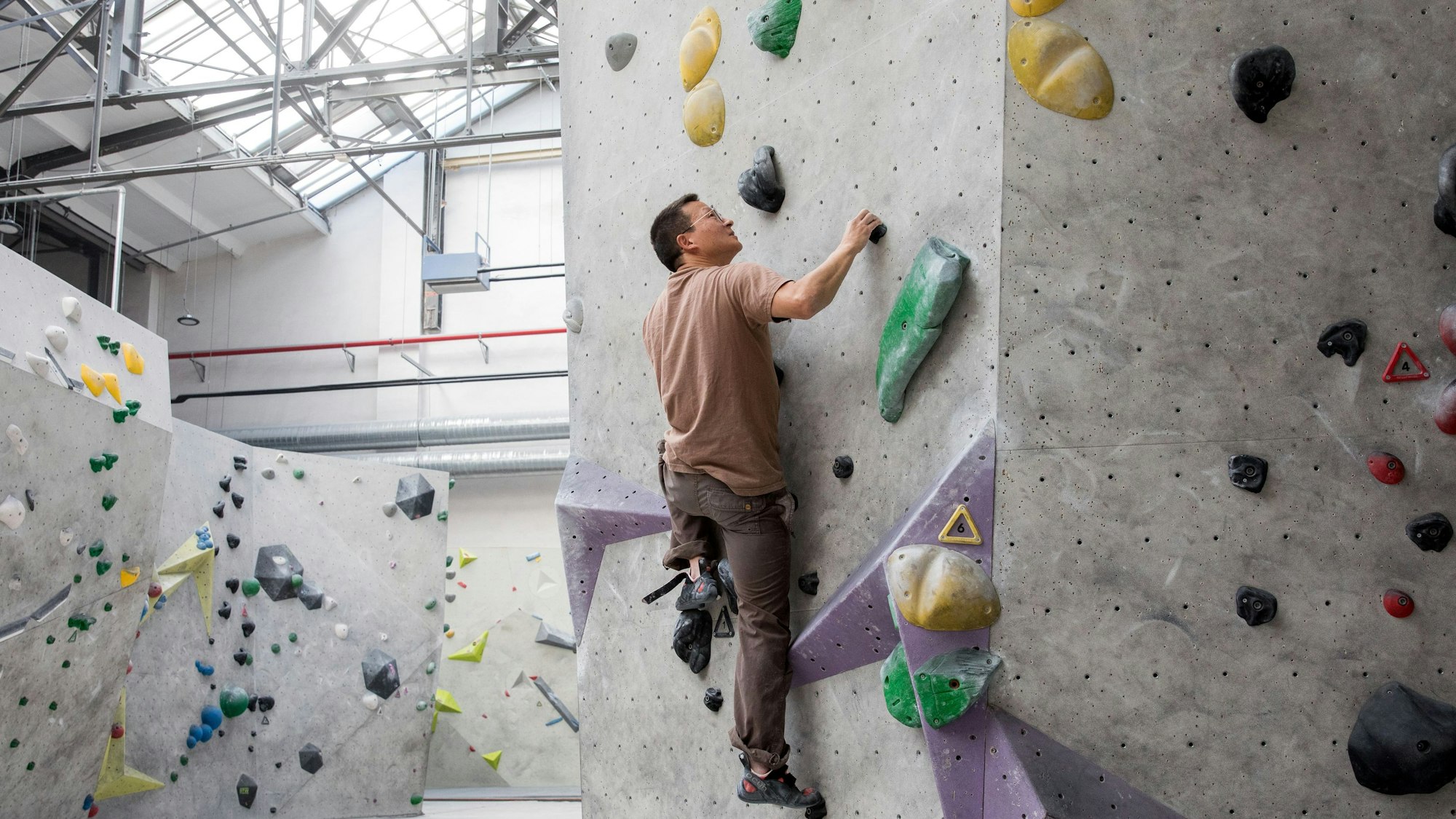 Marc Boppel klettert in der Kletterhalle Stuntwerk in Köln-Mülheim an einem Felsen hoch.
