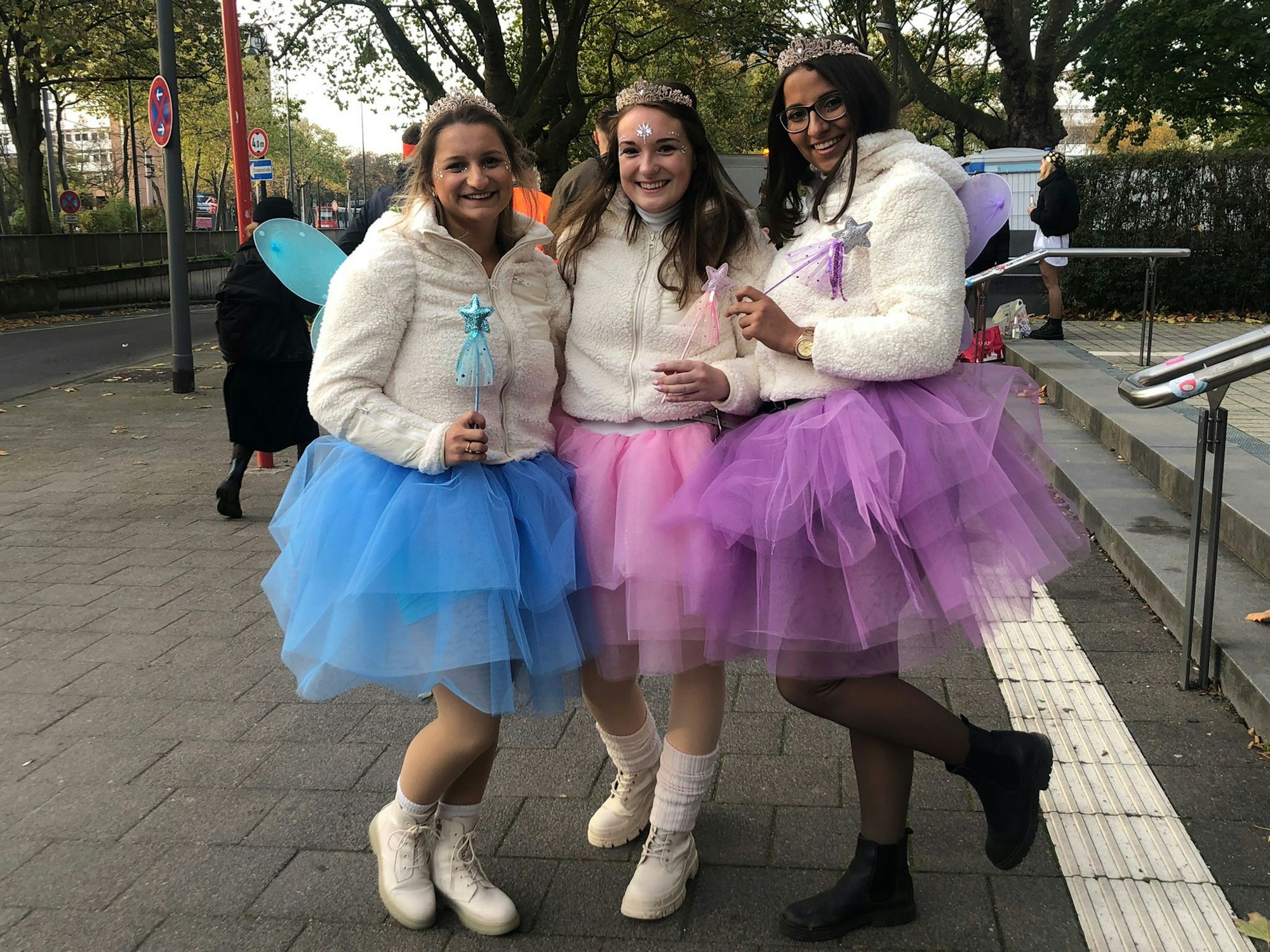 Drei Mädchen in Kostümen posieren für die Kamera. Die drei Freundinnen sind aus Karlsruhe nach Köln angereist.