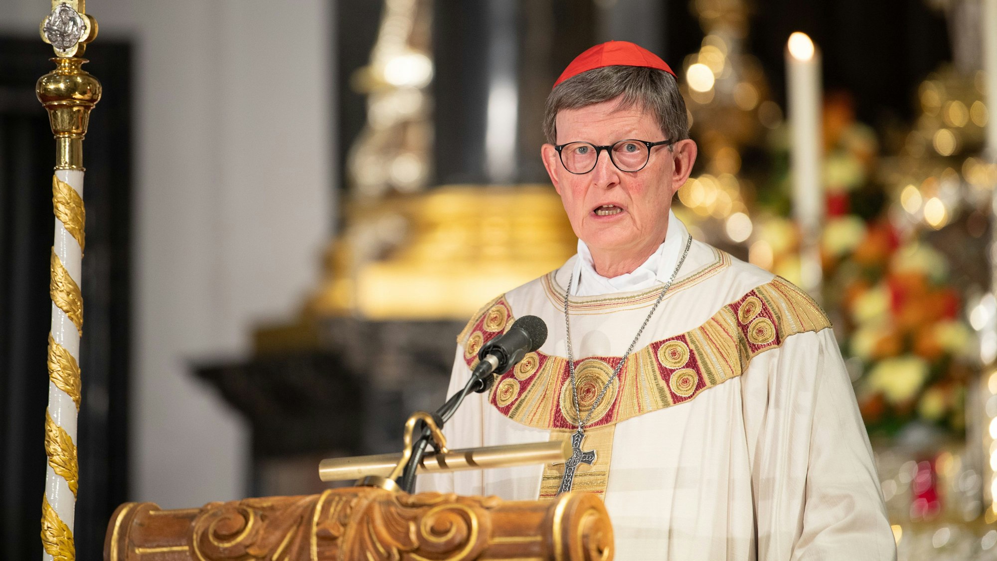 Rainer Maria Kardinal Woelki, Erzbischof von Köln, in festlichem Ornat und rotem Bischofskäppchen, predigt von einer goldverzierten hölzernen Kanzel in einem opulent ausgestatteten Kircheninnenraum.