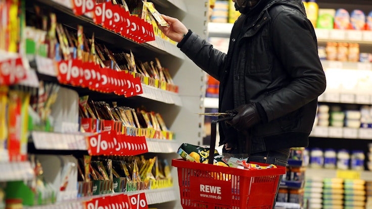 Ein Kunde steht in Köln in einem Rewe-Supermarkt an einem Regal (Symbolfoto).