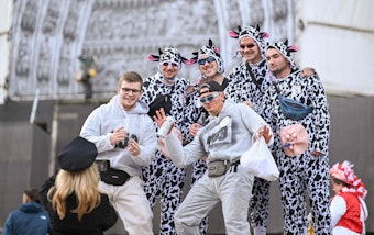 Eine Männergruppe steht auf der Domtreppe. Vier davon tragen Kostüme mit Kuhfleckenmuster. Einer hat ein nachgebildetes Euter umhängen.