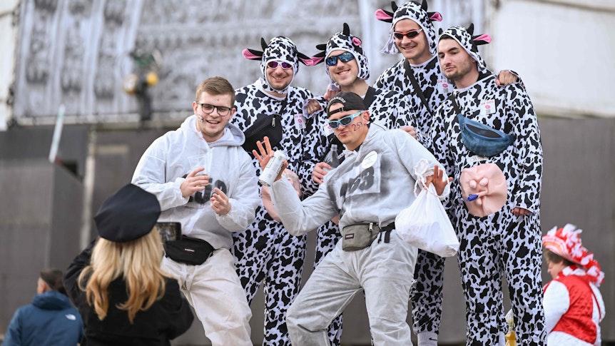 Mehrere Männer sind als Kühe verkleidet und lassen sich von einer Frau vor dem Kölner Dom fotografieren.
