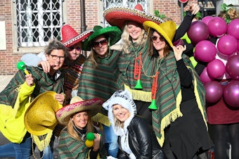 Eine Gruppe trägt mexikanische, sehr große Hüte und hat Umhänge über die Schulter gelegt.
