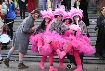 Vier Frauen stehen mit pinken Strumpfhosen und Röcken in der Innenstadt.