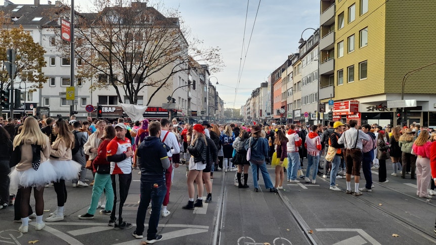 Ein Blick über die Zülpicher Straße. Viele Verkleidete stehen in kleineren Gruppen zusammen.