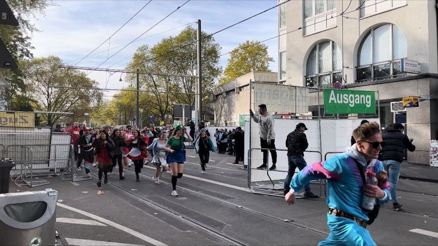 Zahlreiche Karnevalisten stehen an einer Absperrung, da Polizeibeamte den Zugang zur Zülpicher Straße wegen Überfüllung abgeriegelt haben.