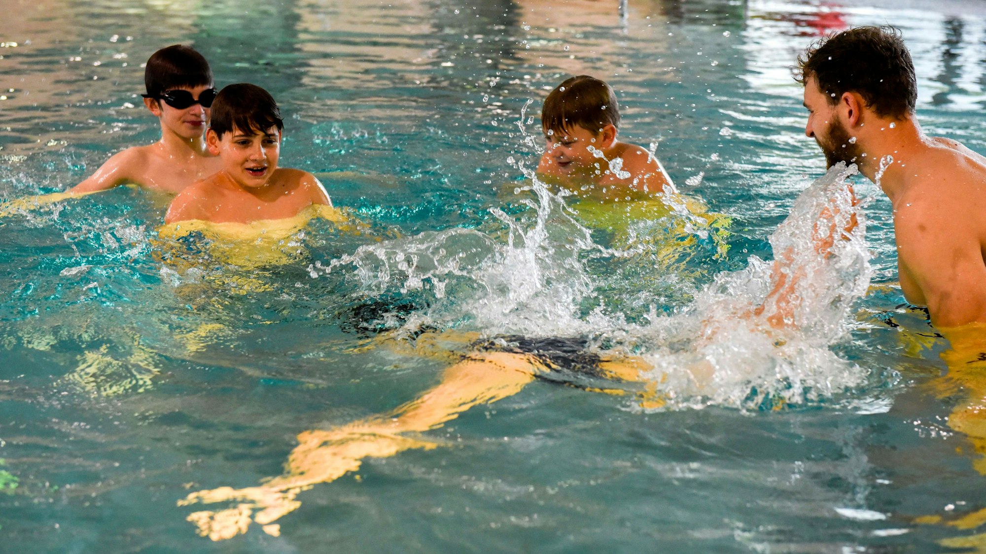 Vier Kinder üben im Wasser mit ihrem Schwimmlehrer.