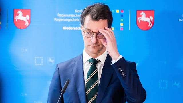 Hendrik Wüst (CDU), Ministerpräsident von Nordrhein-Westfalen,steht vor einem Mikrofon und fasst sich an die Brille.