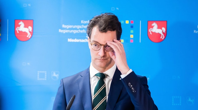 Hendrik Wüst (CDU), Ministerpräsident von Nordrhein-Westfalen,steht vor einem Mikrofon und fasst sich an die Brille.