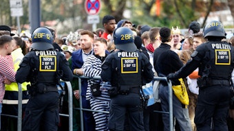 Karnevalisten stehen an einer Absperrung, da Polizeibeamte den Zugang zur Zülpicher Straße wegen Überfüllung abgeriegelt haben. Der Karnevalsauftakt zum 11.11. hat in Köln wie erwartet zu einem Massenandrang geführt
