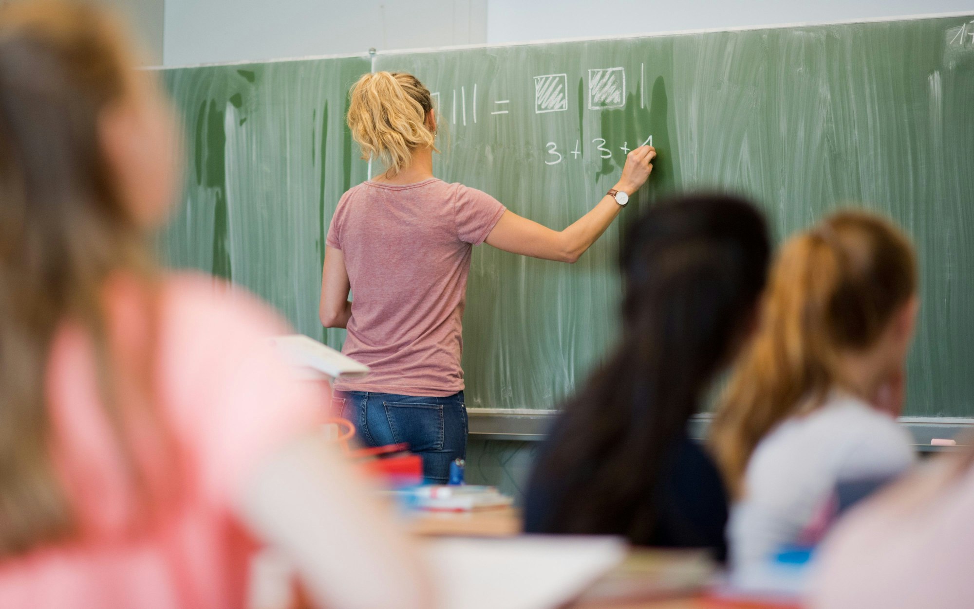 Eine Lehrerin schreibt im Mathematikunterricht einer achten Klasse an eine Schultafel.