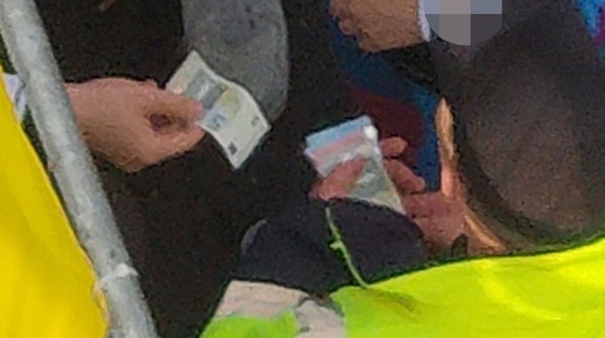 Ein Ordner nimmt einen Fünf-Euro-Schein von einem Feiernden entgegen. Die Szene wurde am 11.11.2022 am Ausgangsbereich der Zülpicher Straße aufgenommen.