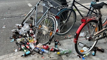 Rund um ein paar abgestellte Fahrräder liegen Dutzende umgestoßene und teilweise zerbrochene Bierflaschen.