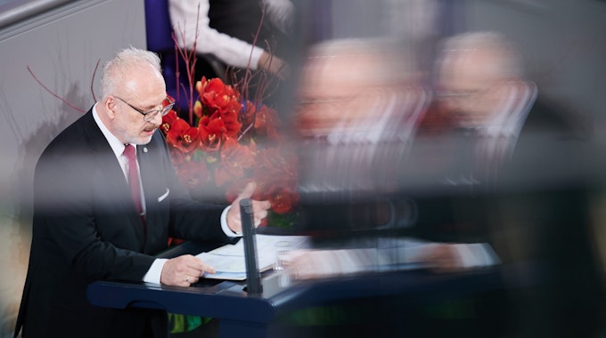 Der lettische Staatspräsident Egils Levits steht am Rednerpult des Bundestags in Berlin, neben ihm ein Strauß roter Blumen.
