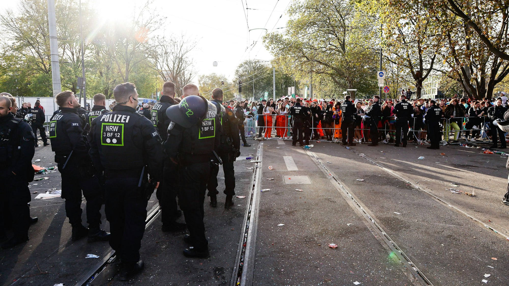 Polizisten und Feiernde stehen am 11.11. auf den gesperrten Gleisen der KVB an der Unimensa in Köln.