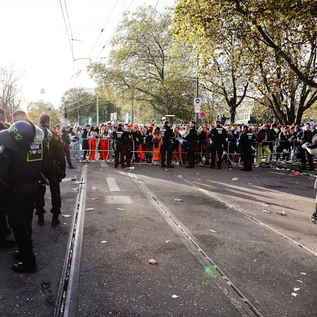 Polizisten und Feiernde stehen am 11.11. auf den gesperrten Gleisen der KVB an der Unimensa in Köln.