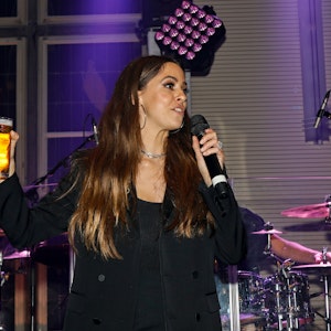 Vanessa Mai steht mit Bierglas und Mikrofon in der Hand auf der Bühne der Blauen Funken in Köln.