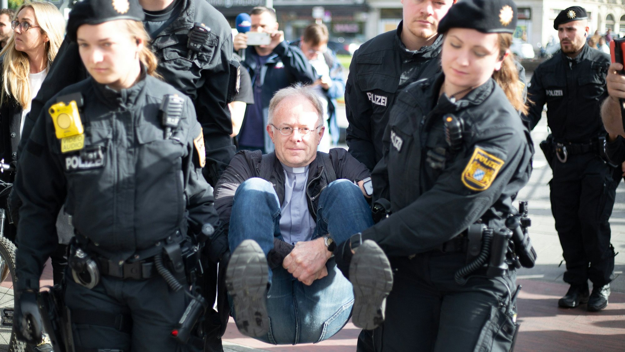 Vier Polizistinnen und Polizisten tragen Jörg Alt von einer Straße, die er am 28. Oktober 2022 in München mit anderen Klimaaktivistinnen und -aktivisten blockiert hatte.