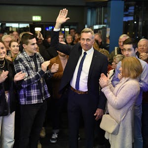 Ralph Manzke, neuer Bürgermeister in Wesseling, steht vor zahlreichen Menschen und feiert seinen Wahlsieg. Er trägt einen Anzug mit blauer Krawatte.