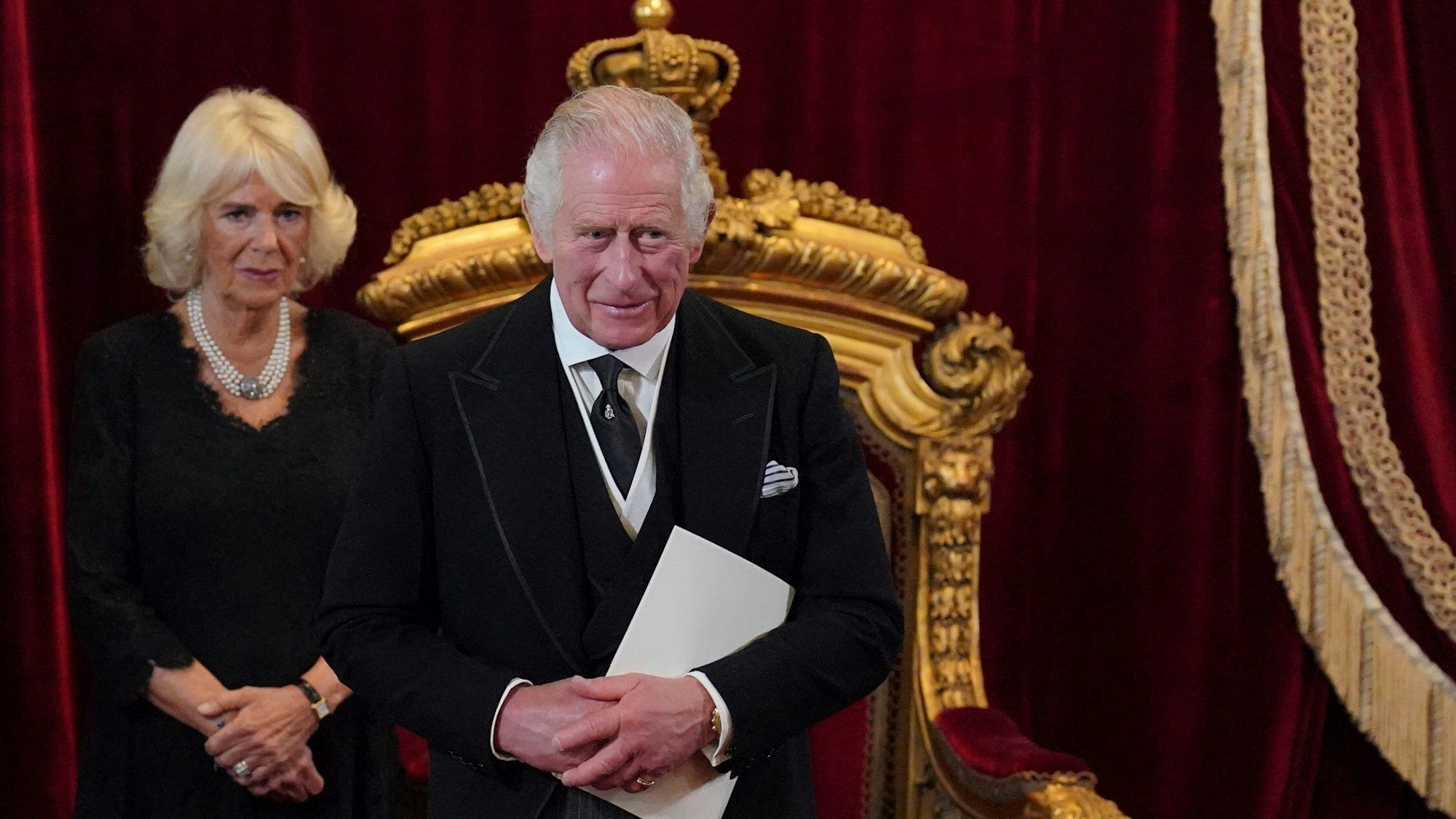 König Charles III. und Königsgemahlin Camilla stehen vor dem Thron.