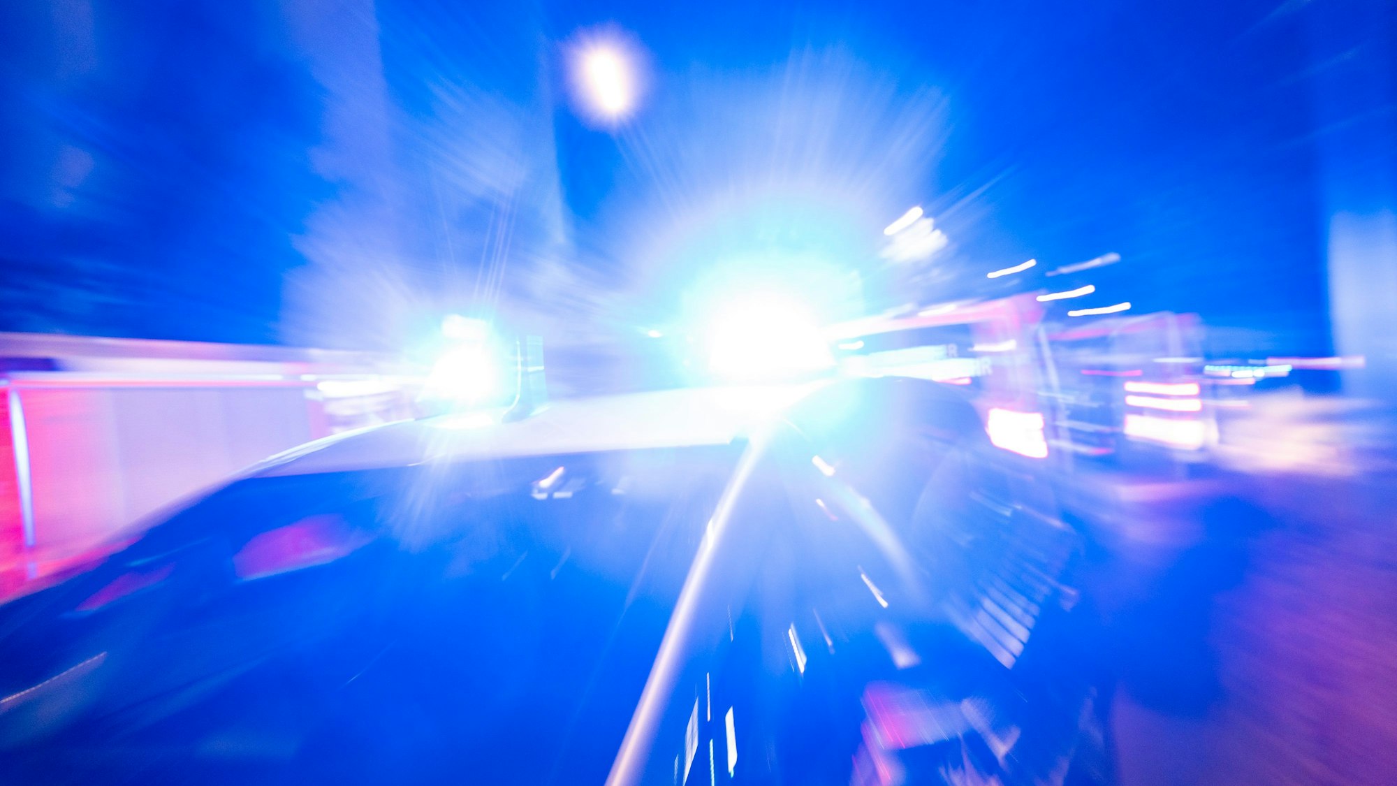Ein Polizeiauto fährt mit Blaulicht durch die Nacht.