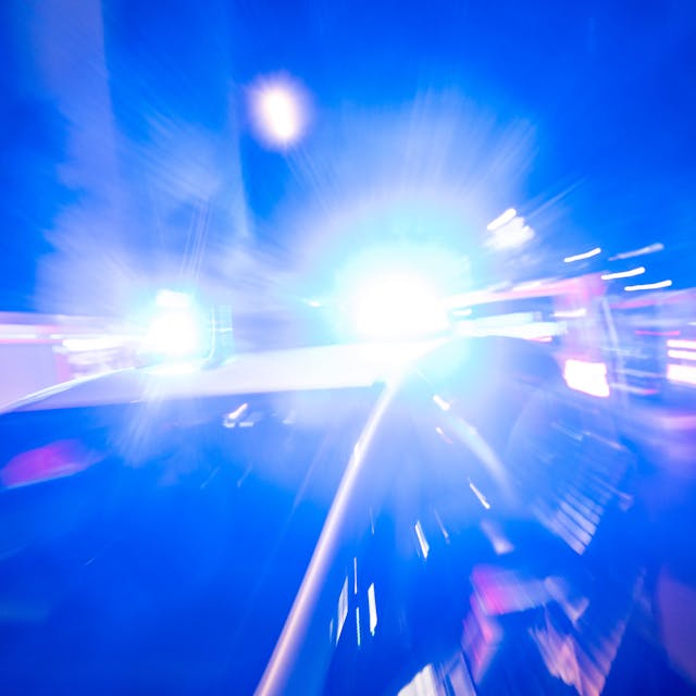 Ein Polizeiauto fährt mit Blaulicht durch die Nacht.