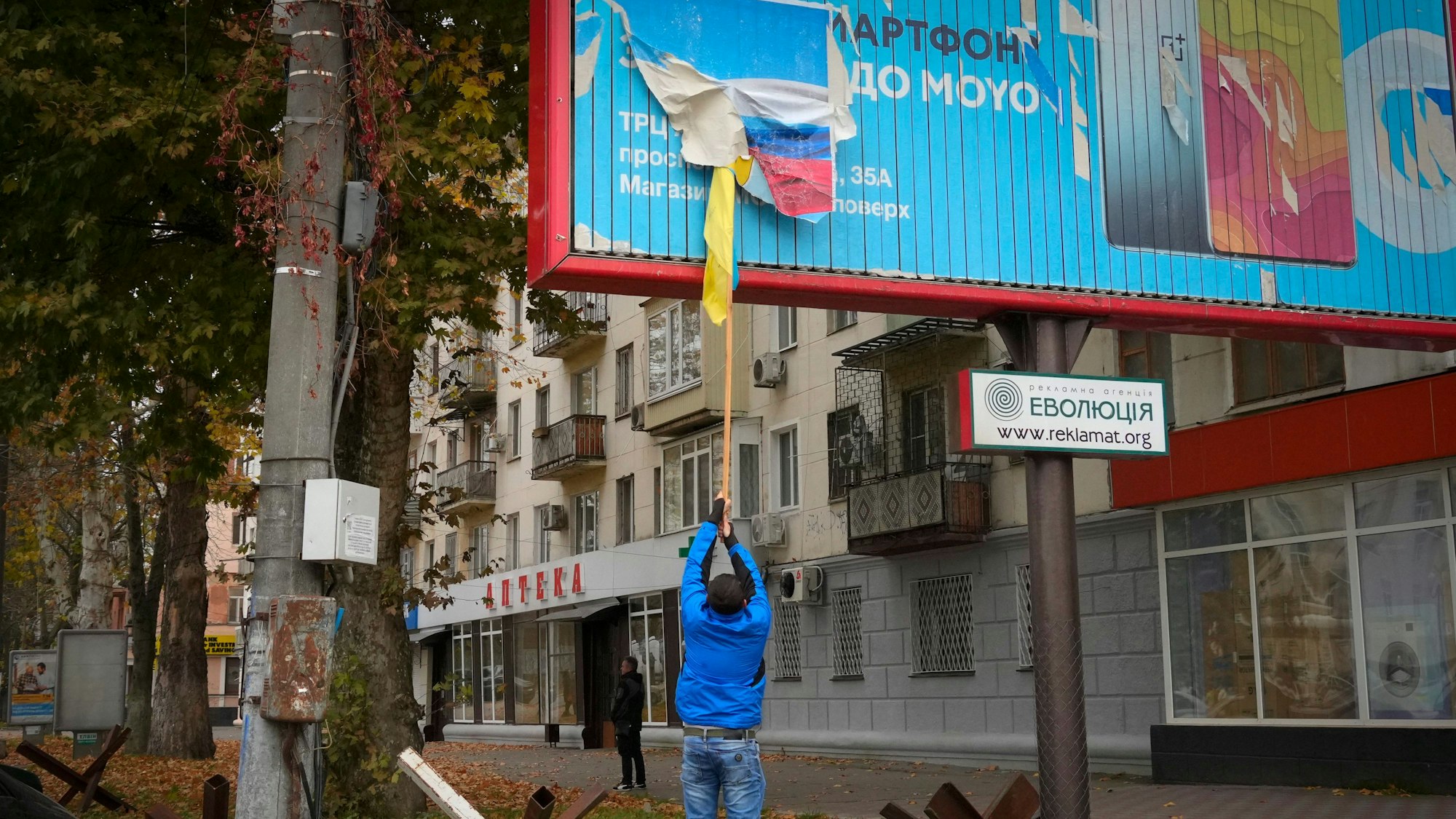 Ein Anwohner entfernt die russische Flagge von einer Plakatwand in Cherson.