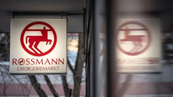 Eine Leuchttafel mit dem Firmenlogo hängt an eine Filiale der Drogeriemarktkette Rossmann in der Mainzer Innenstadt.