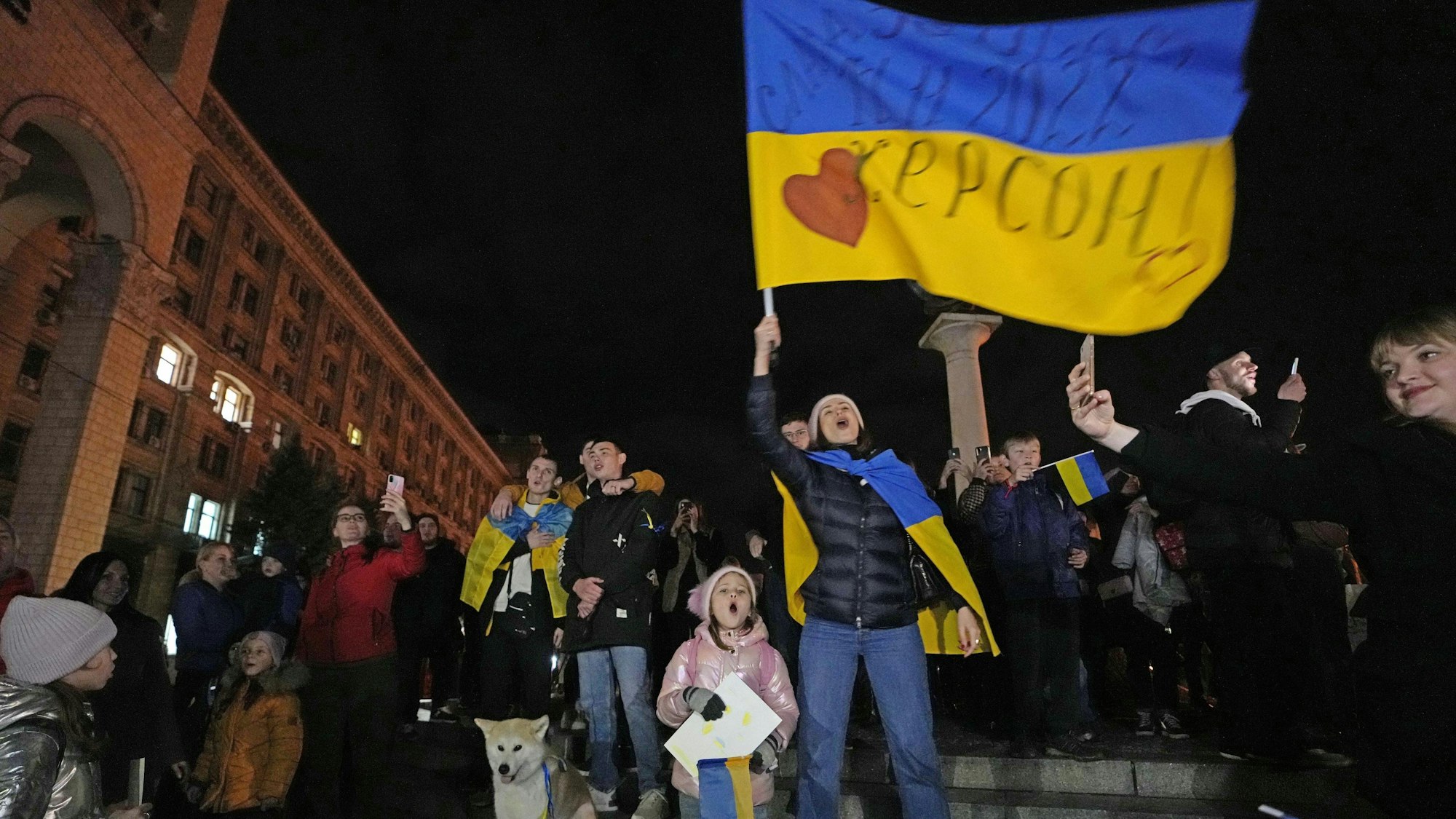 Kiew: Menschen feiern und schwenken eine ukrainische Fahne, nachdem sie erfahren haben, dass ukrainische Truppen in die südliche Stadt Cherson, die Hauptstadt der Ende September von Russland annektierten Region Cherson, eingedrungen sind.