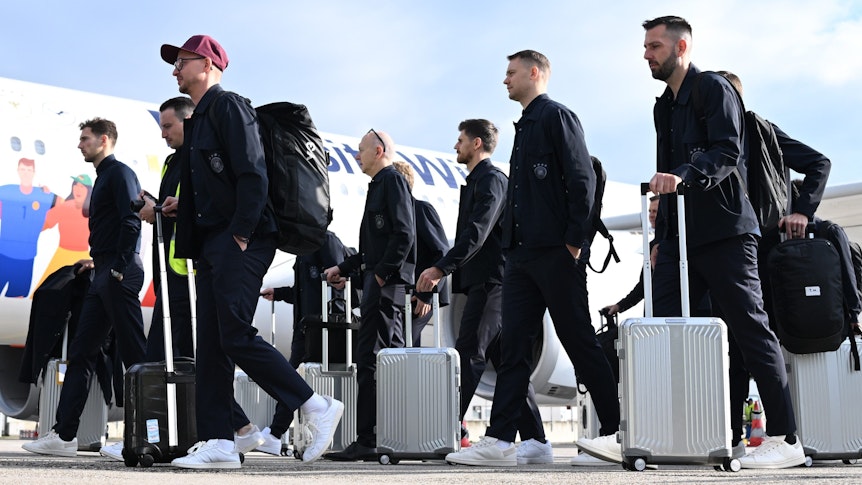 Trainer, Offizielle, Betreuer und Spieler der deutschen Fußball-Nationalmannschaft, unter ihnen Kapitän Manuel Neuer (2.v.r.), laufen zum Flugzeug.