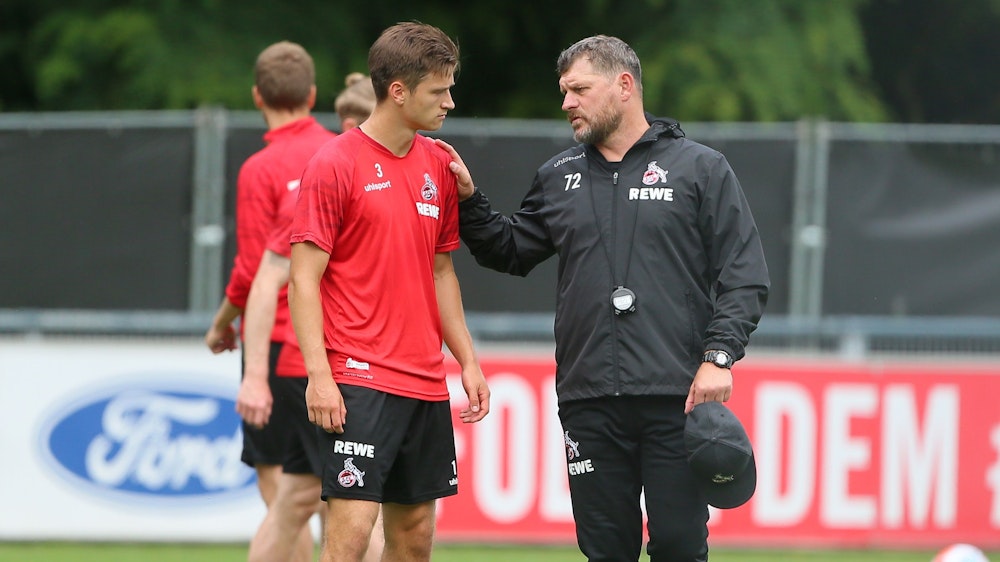 Steffen Baumgart spricht beim Training des 1. FC Köln mit Noah Katterbach.