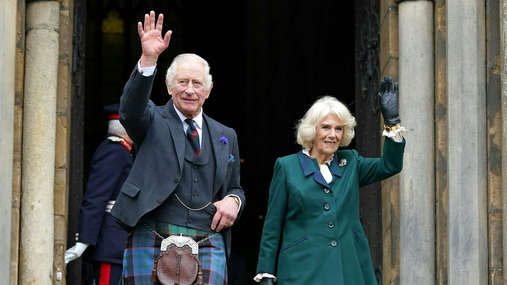 König Charles III. im Schottenrock und Königsgemahlin Camilla winken beim Verlassen der Abbey von Dunfermline.