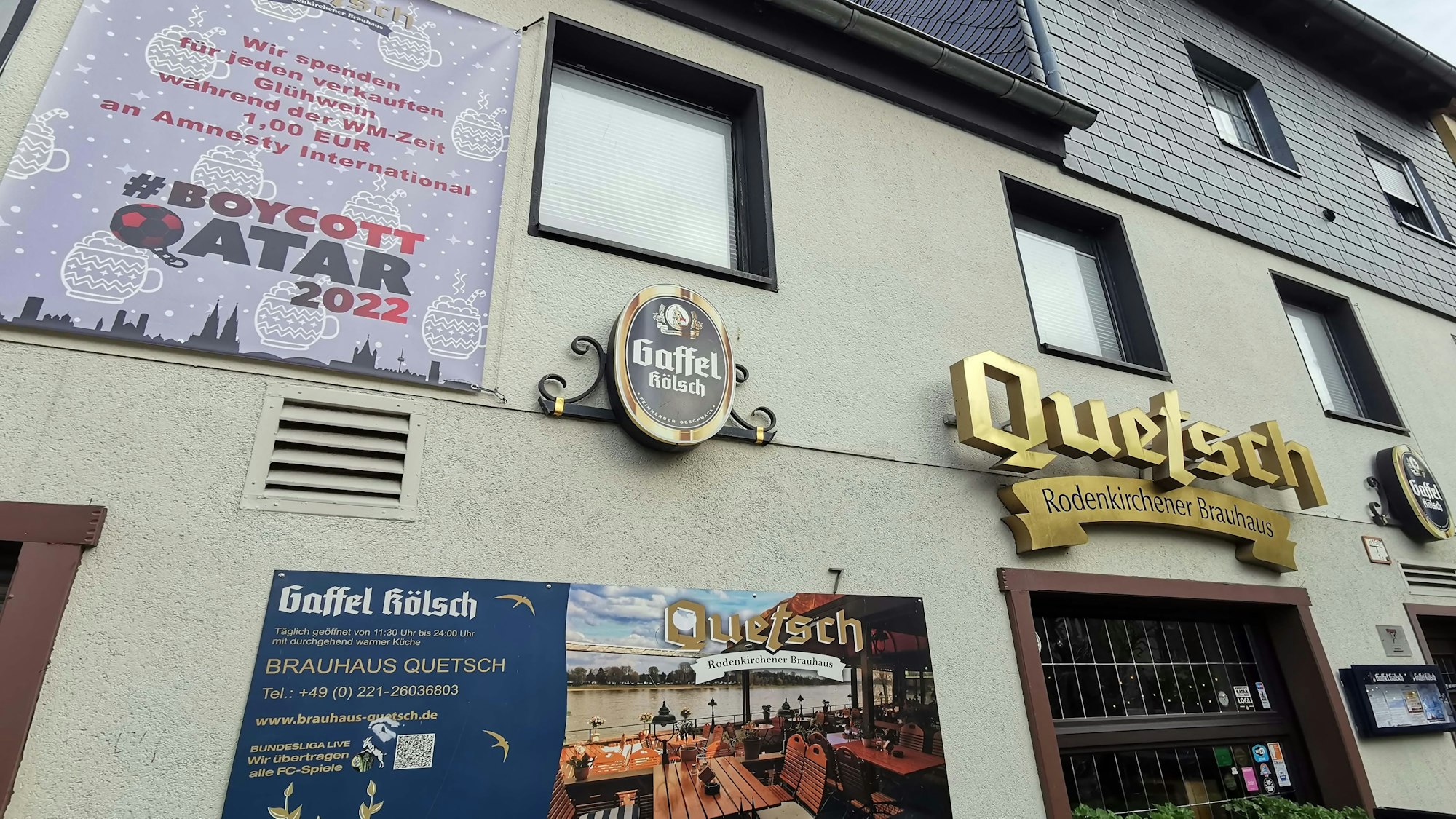 Ein WM-Boykott-Plakat hängt an der Fassade der Wirtschaft „Quetsch“ in Rodenkirchen