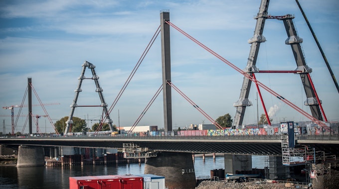 Die neue Rheinbrücke für die Autobahn 1 zwischen Köln und Leverkusen im Oktober 2022. Ein Pylon steht, ein zweiter wird gerade aufgebaut. Dazu hängt ein Kran eine Arbeitsplattform ein.