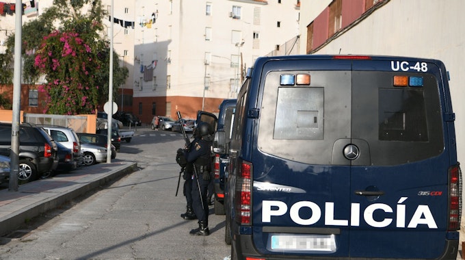 Ein Polizeiwagen und Beamte der Nationalen Polizei stehen während eines Polizeieinsatzes auf einer Straße.
