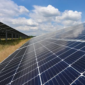Zu sehen ist ein Solarpark mit großen schräg aufgestellten Photovoltaikflächen.&nbsp;