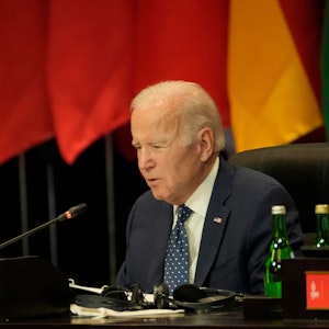 Das Foto zeigt den US-Präsident Joe Biden während des G20-Gipfels. Er spricht in ein Mikrofon, hinter ihm befinden sich Flaggen.